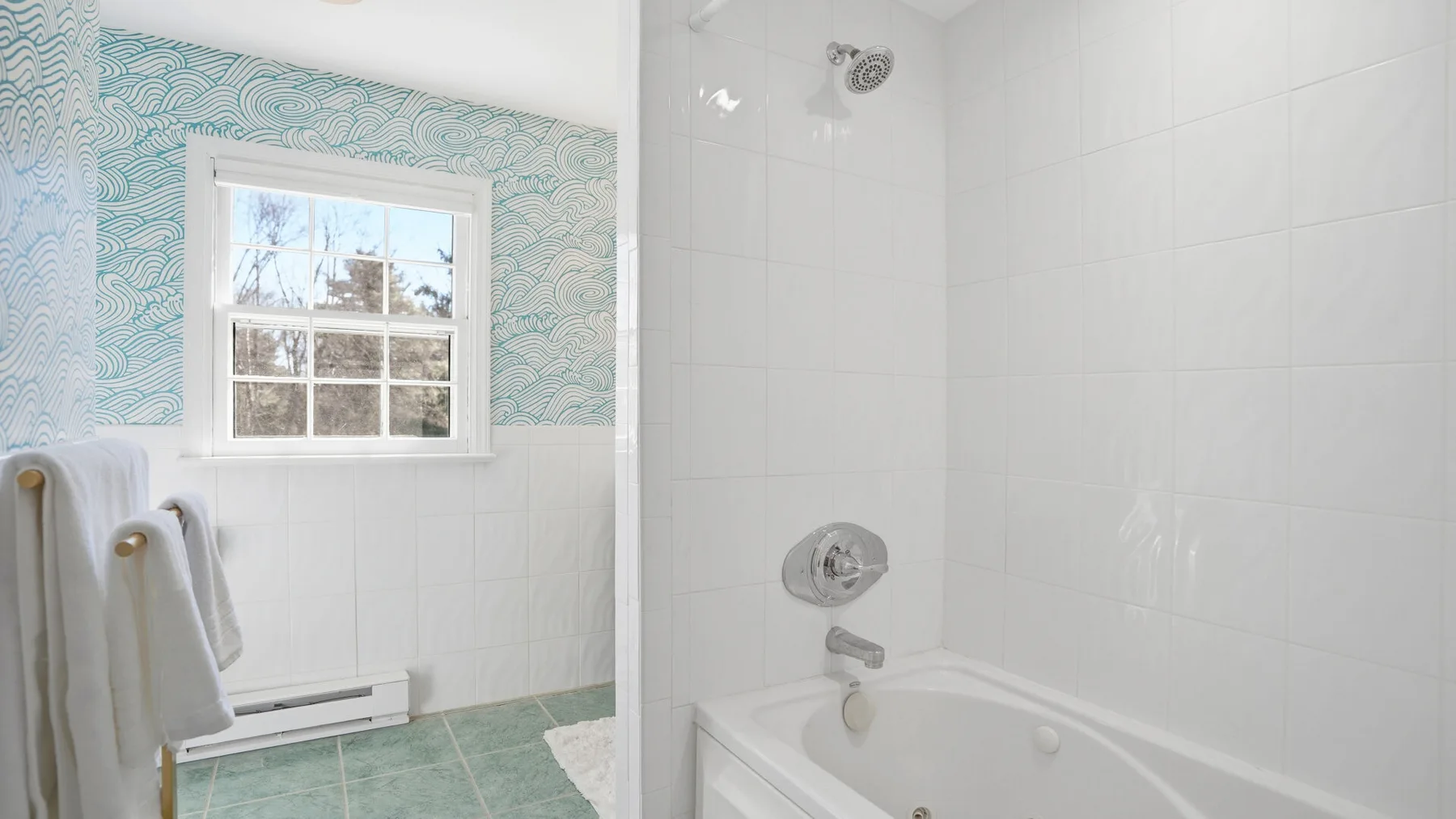 A tiled bathroom with a bathtub, shower, and window.