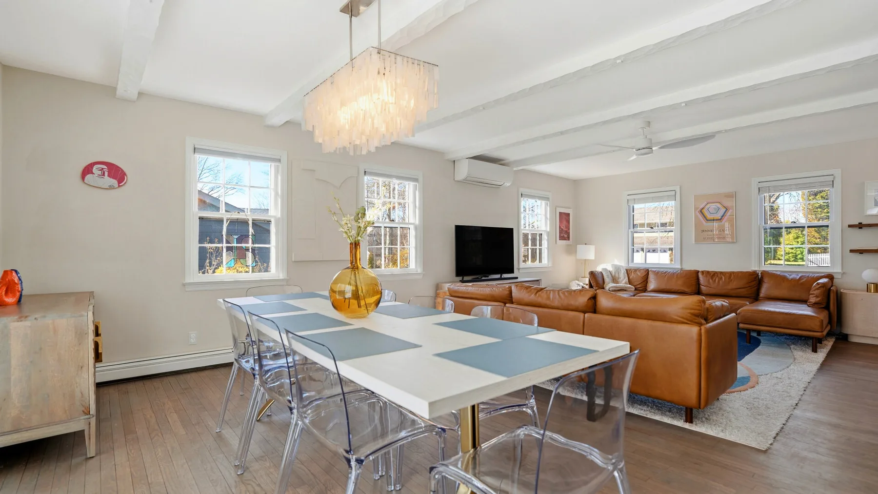 A bright living and dining area with a long table and brown seating.