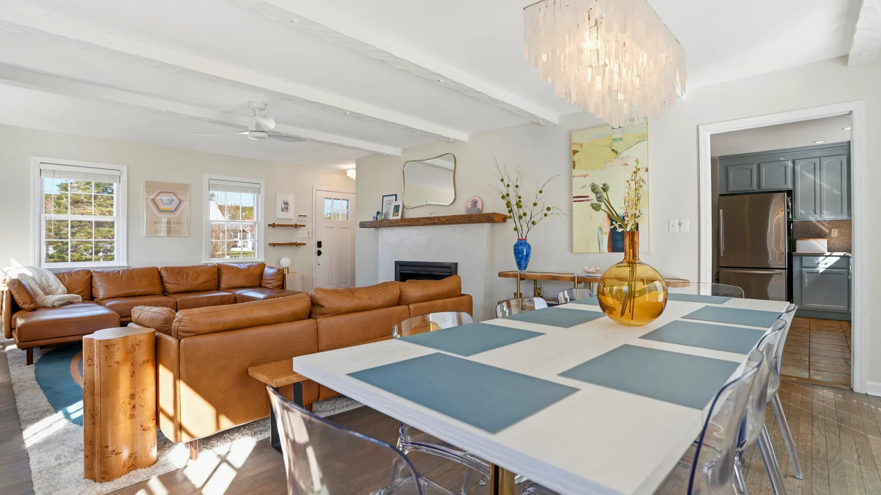 A bright living and dining area with brown seating and a table set with placemats.