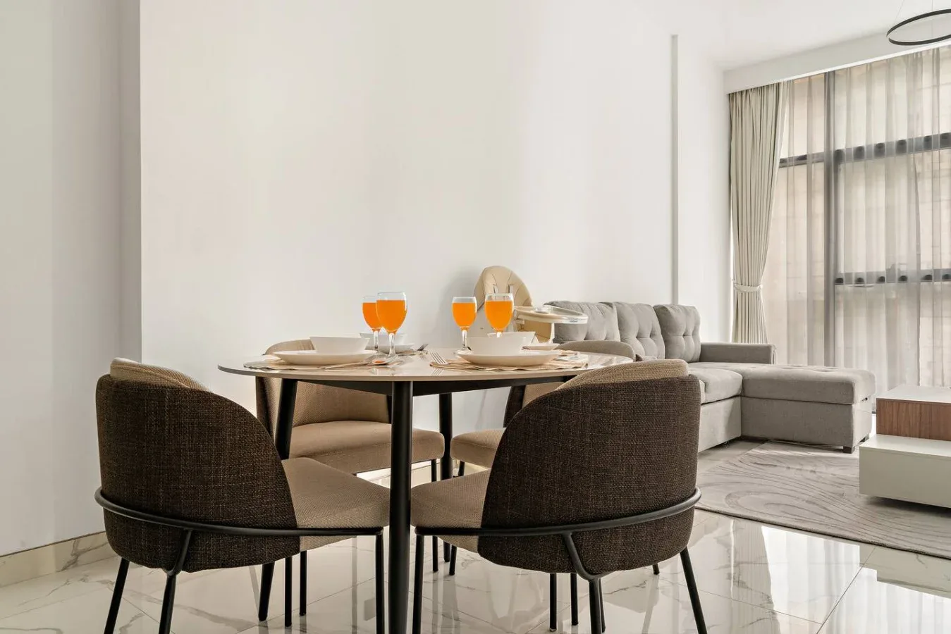 Un comedor con la mesa puesta y una zona de estar junto a una ventana grande.