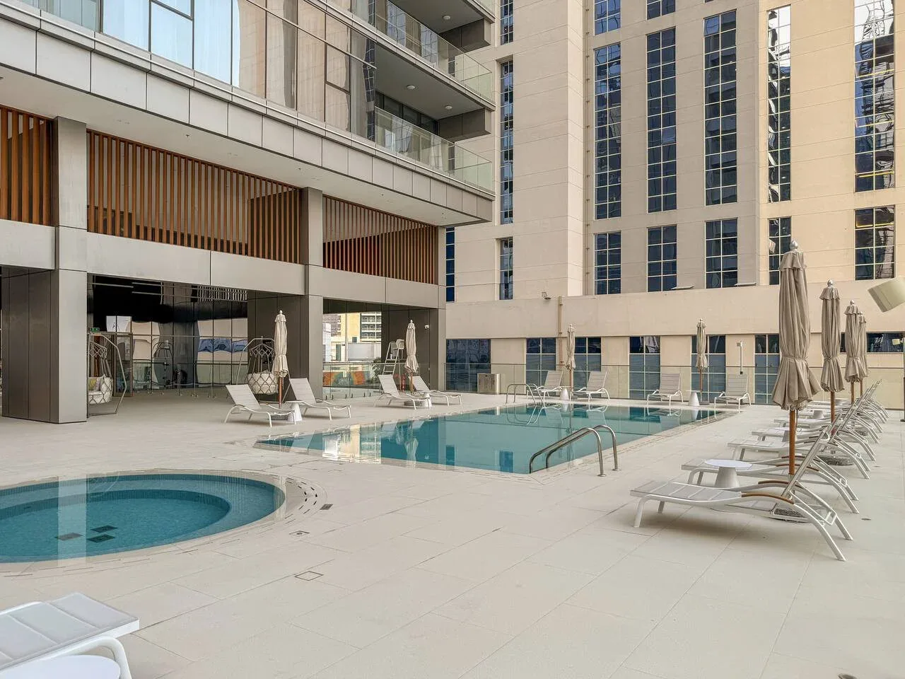 Un patio con piscina al aire libre y asientos junto a edificios modernos.