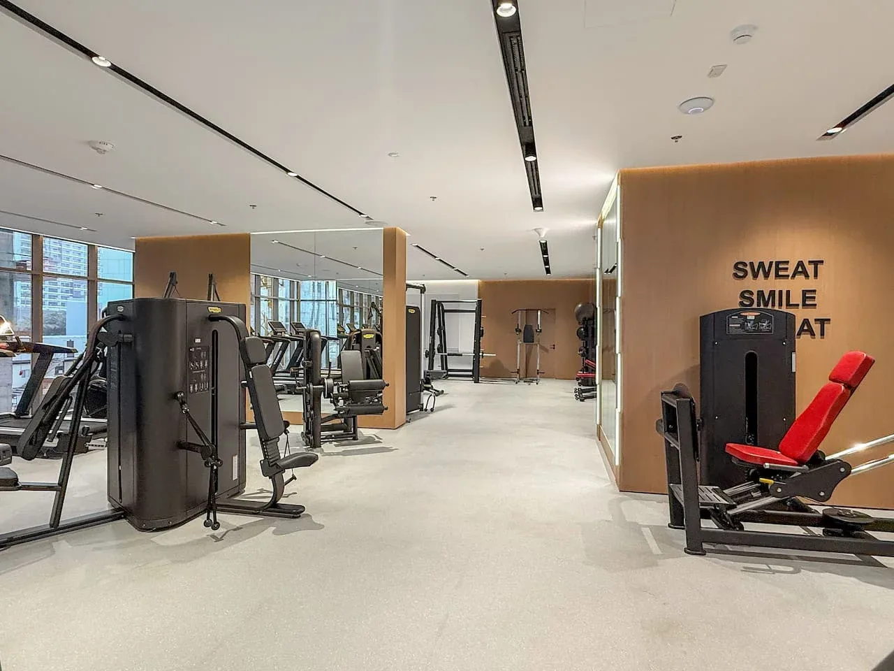Un gimnasio amplio con máquinas de ejercicio y una máquina de pesas con asiento rojo.