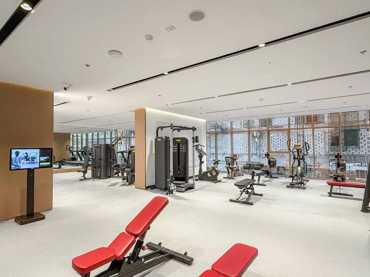 Un gimnasio luminoso con máquinas de pesas y bancos de ejercicio acolchados en rojo.