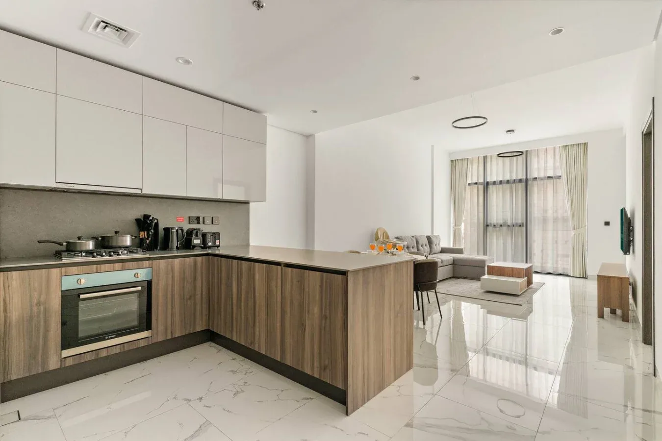 Una cocina moderna se abre a una sala de estar con asientos y grandes ventanas.