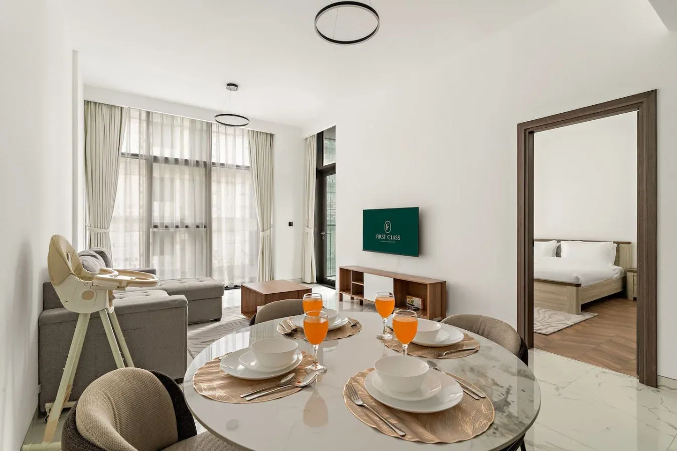 Una luminosa sala de estar y comedor con un televisor y un dormitorio visible a través de la puerta.