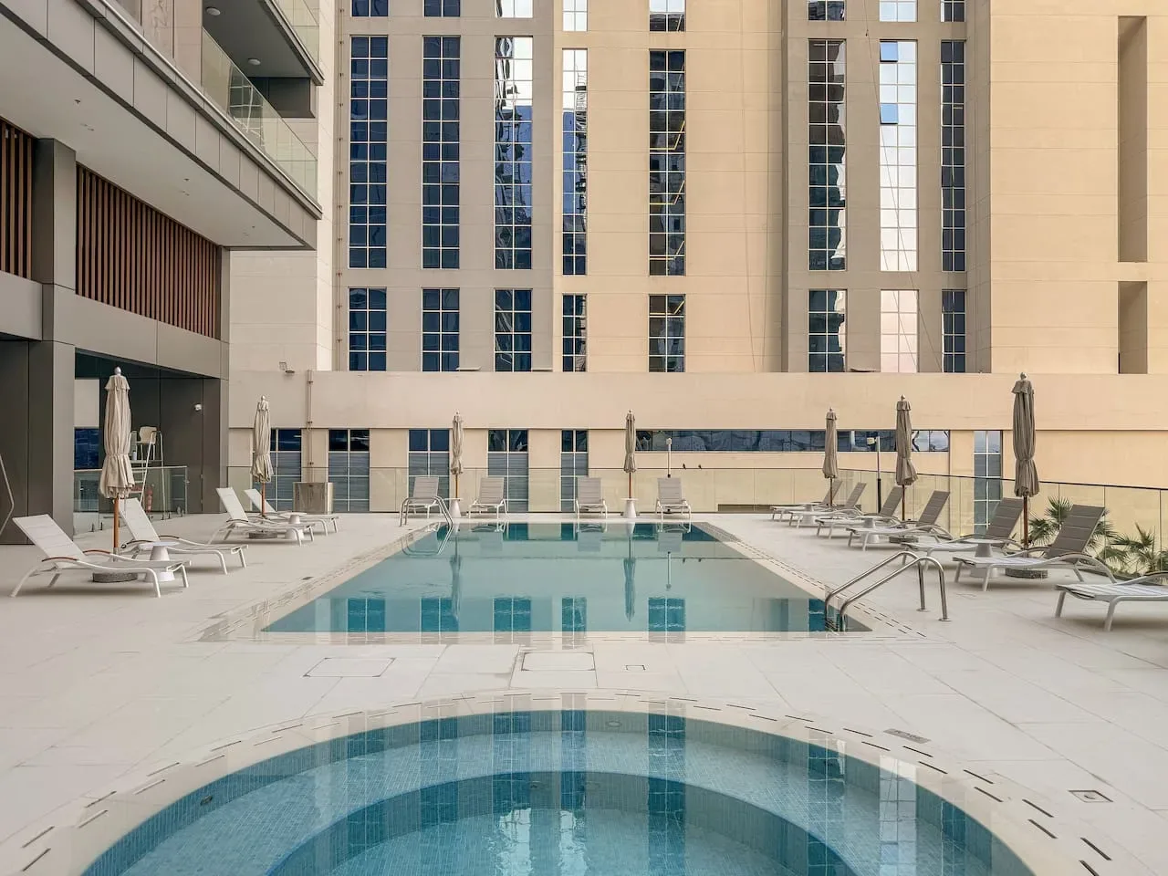 Una piscina al aire libre está en un patio pavimentado rodeado de edificios altos.