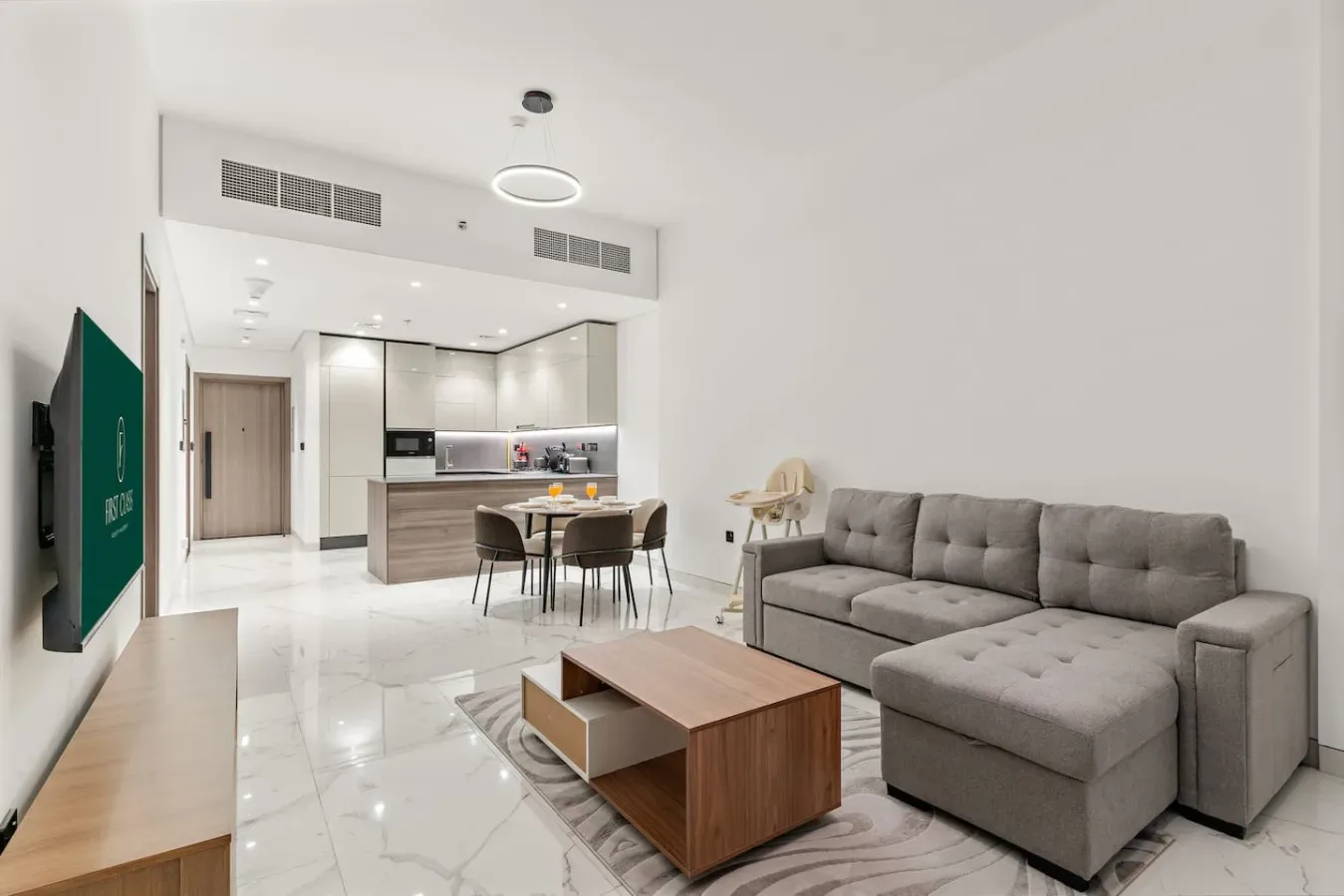 Una luminosa sala de estar y cocina de concepto abierto con sofá seccional y mesa de comedor.
