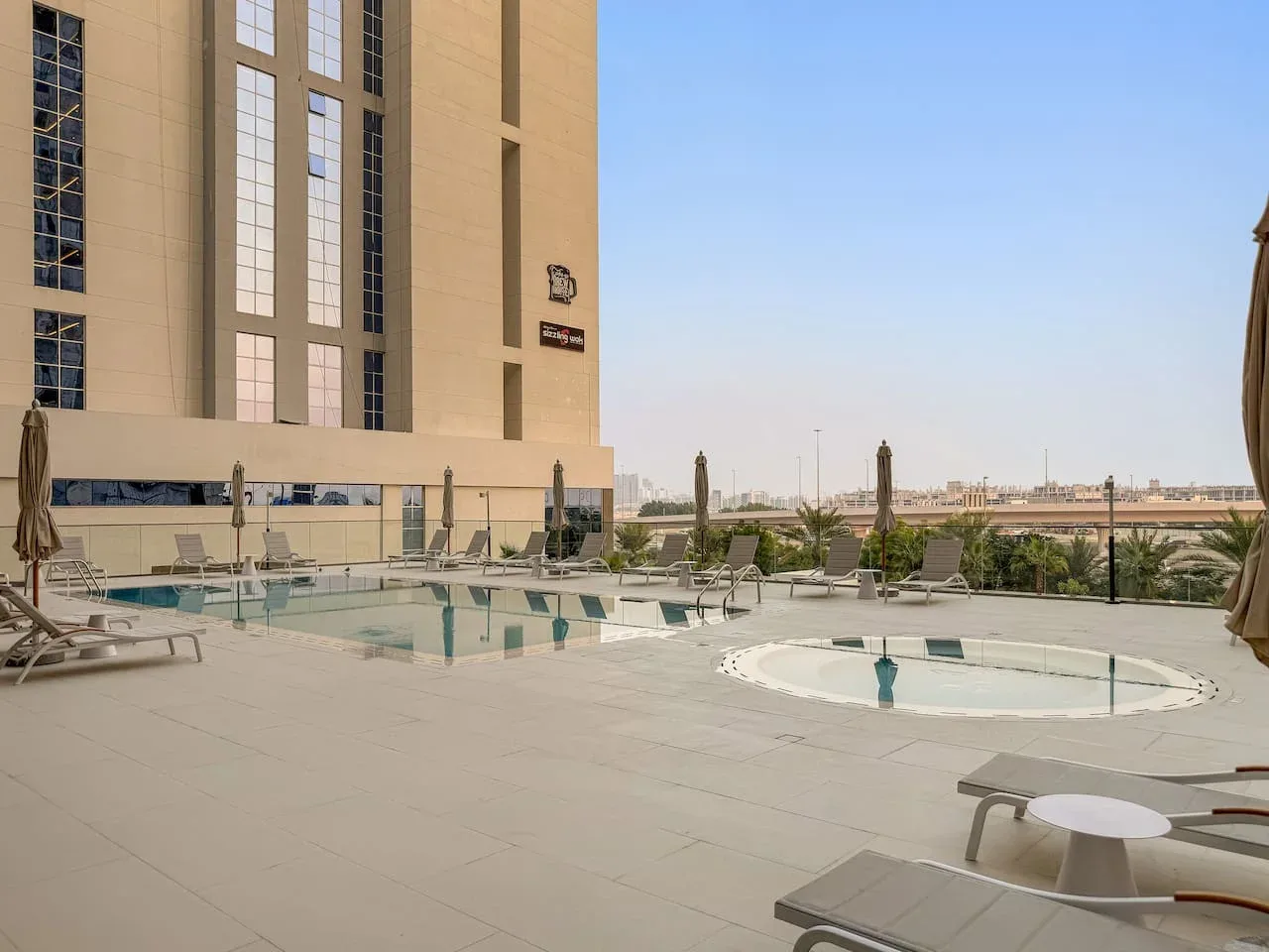 Una terraza con piscina al aire libre, asientos y vistas de la ciudad.