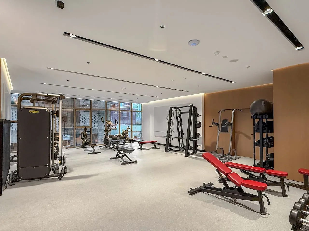 Un gimnasio con máquinas de ejercicio y bancos rojos.