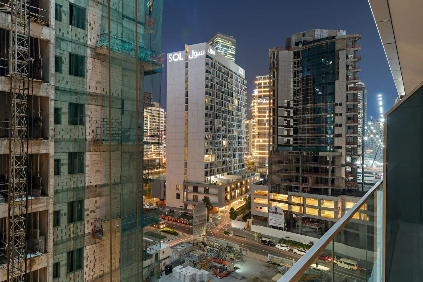 Una vista nocturna de la ciudad muestra edificios altos iluminados y obras de construcción.