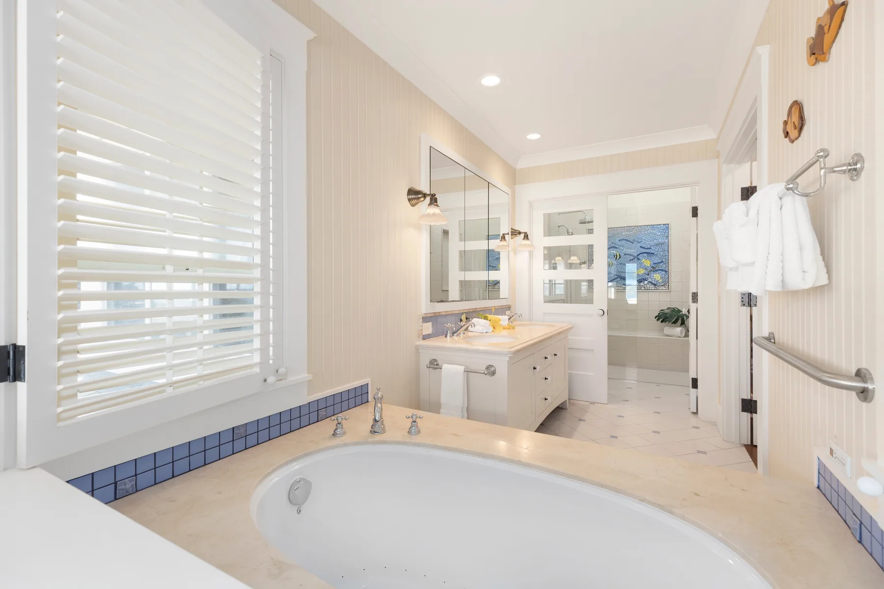 Un baño luminoso con bañera, lavabo y una ventana amplia.