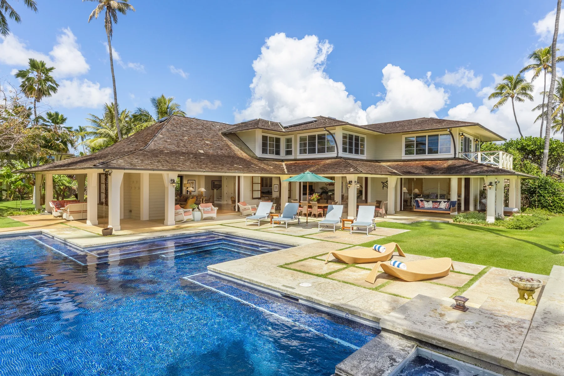 A tropical house with a swimming pool and outdoor seating.