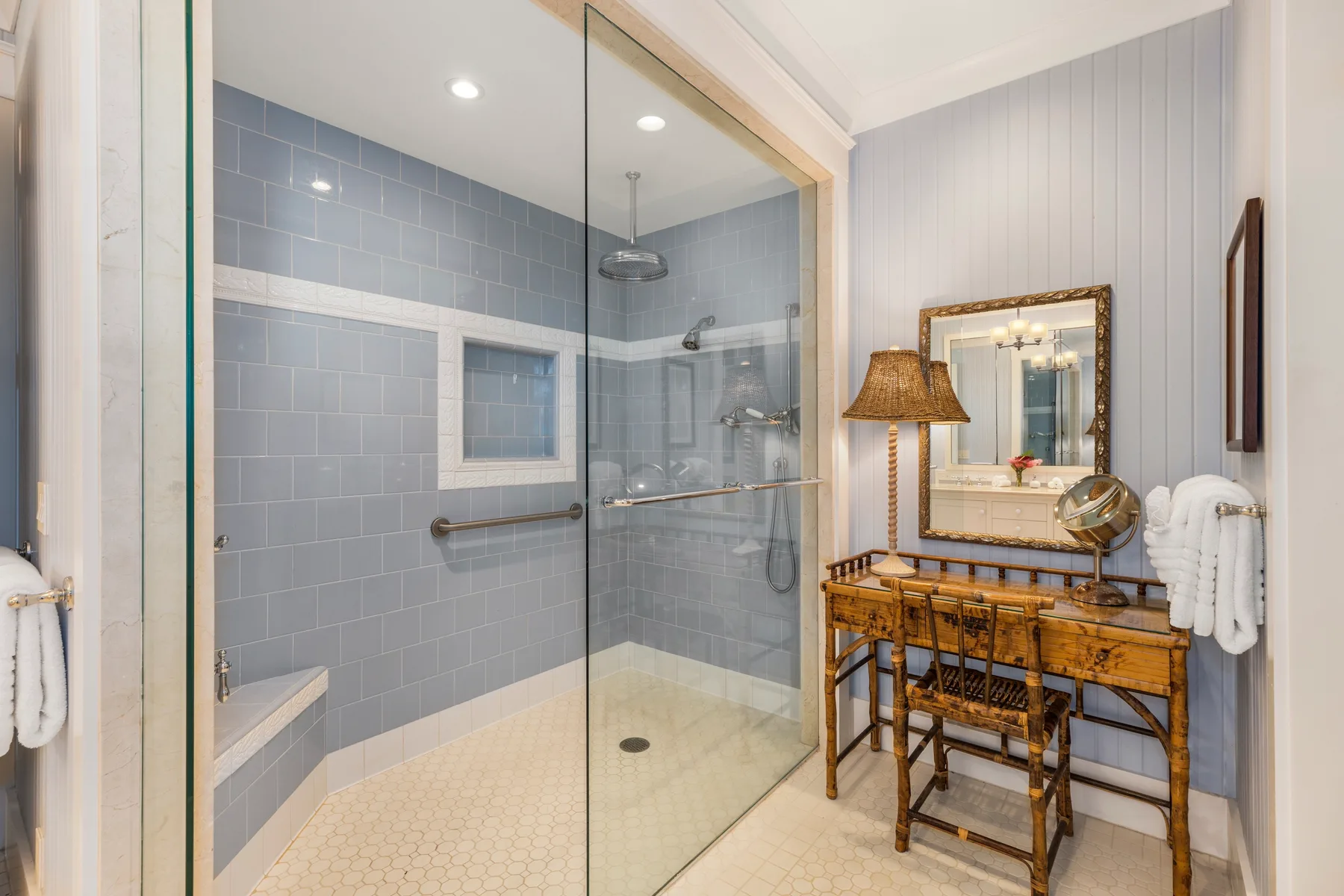 Un baño con una ducha de vidrio y un tocador de madera.