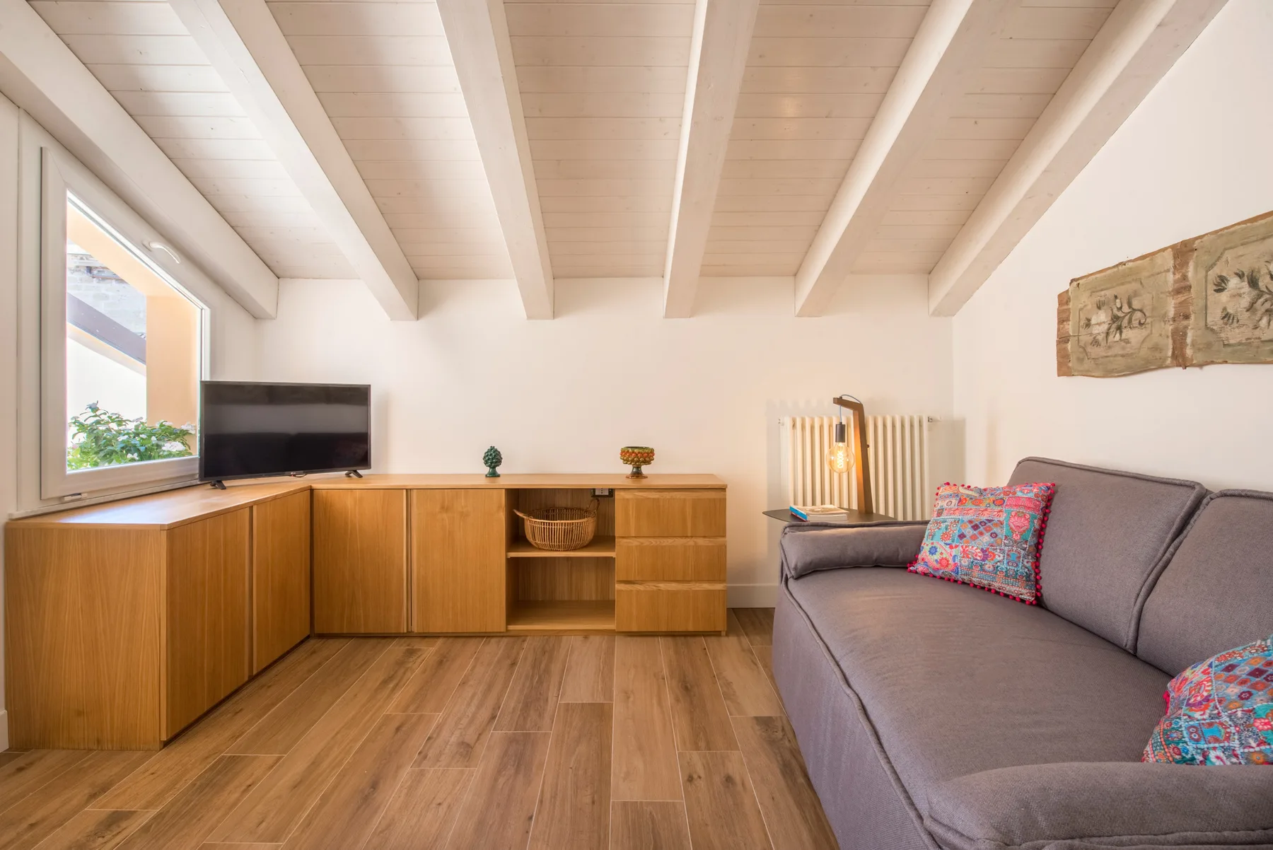 Una sala de estar con un sofá gris y muebles de madera.