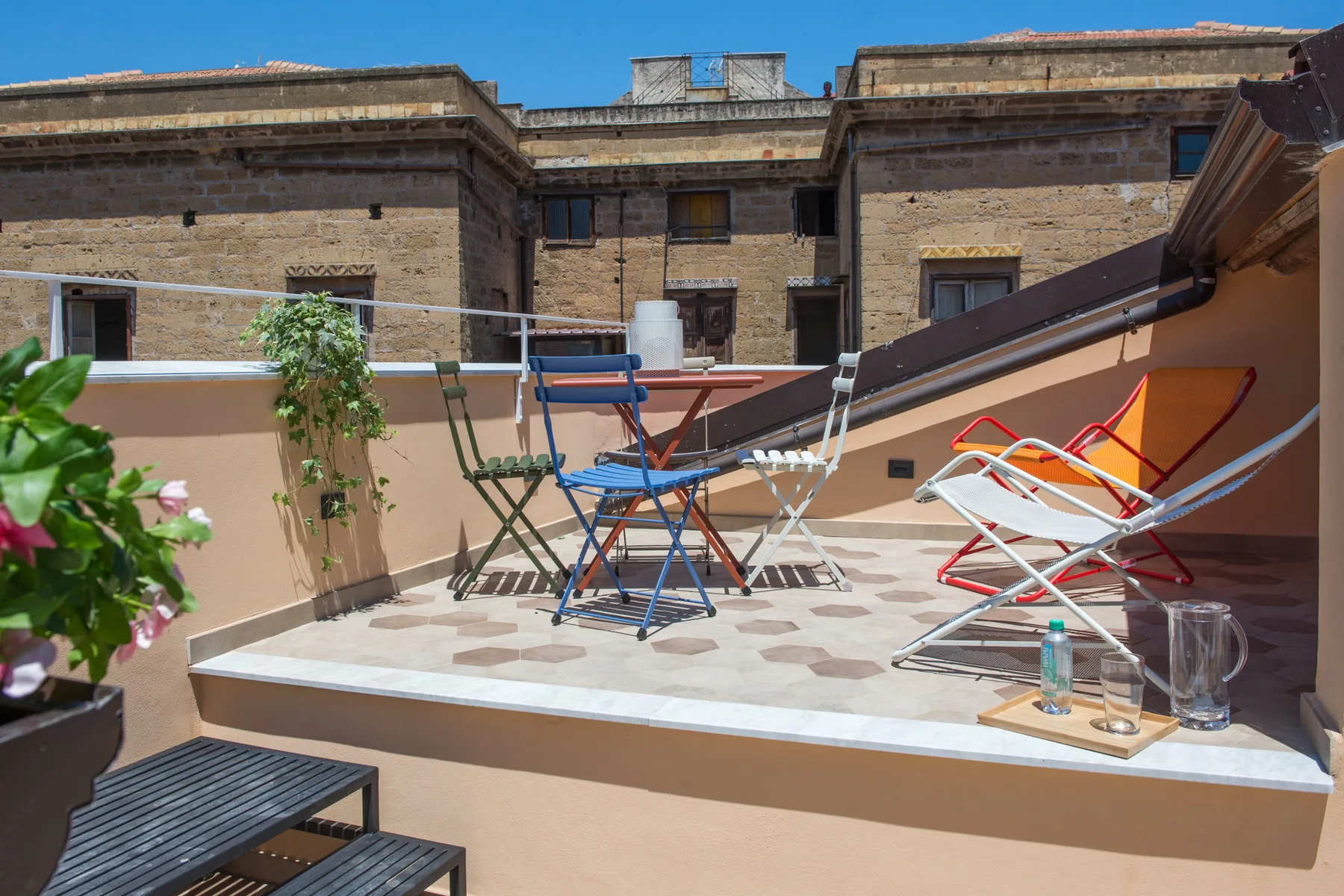 Una terraza en la azotea con asientos al aire libre y cielo azul despejado.