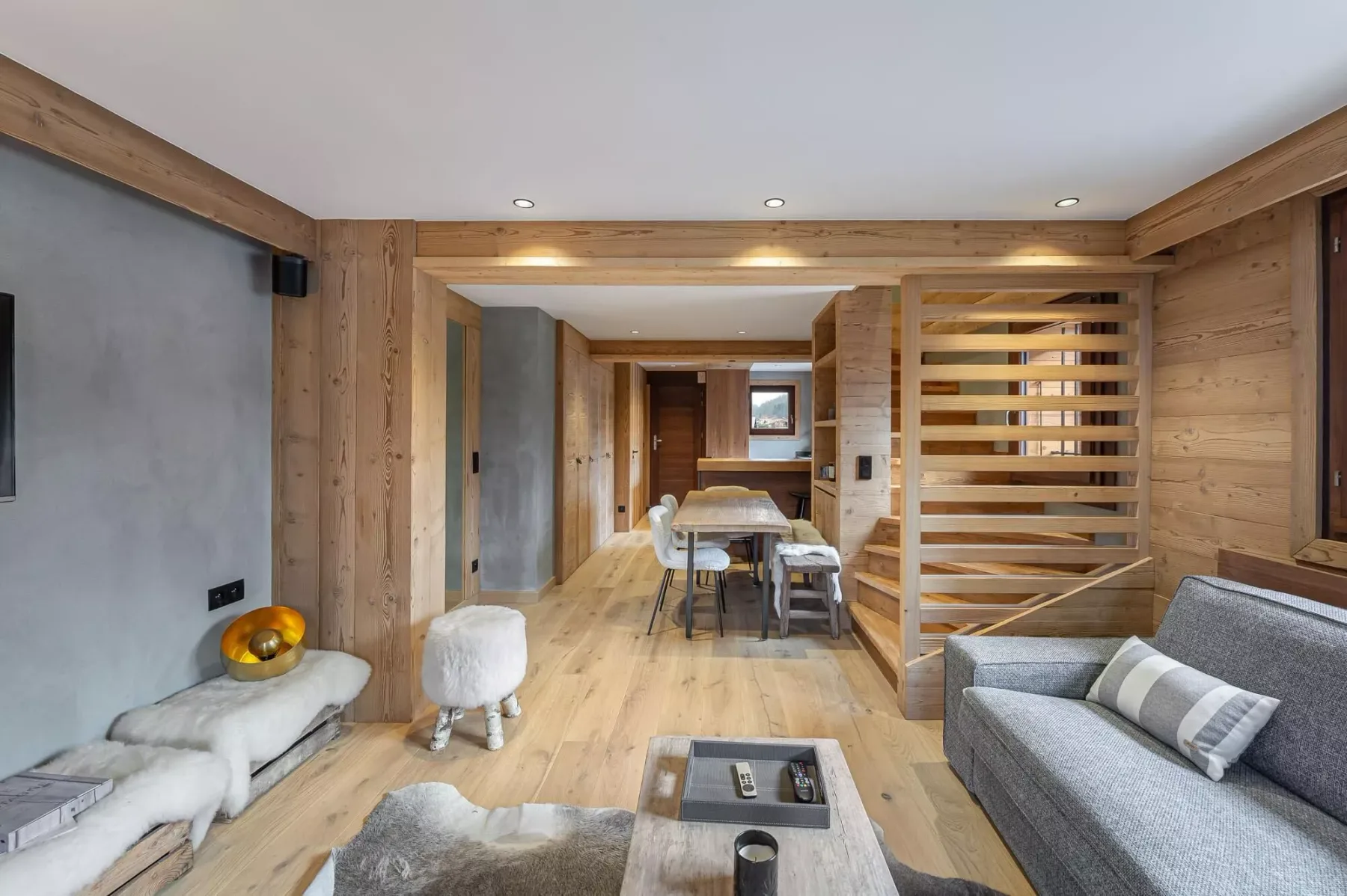Una sala revestida de madera con una mesa de comedor y asientos grises.