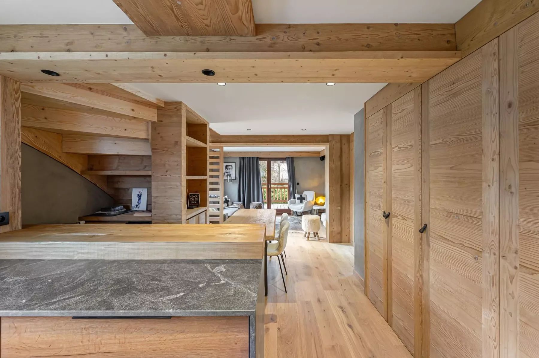 Cocina y comedor revestidos de madera, con una barra larga y una mesa.