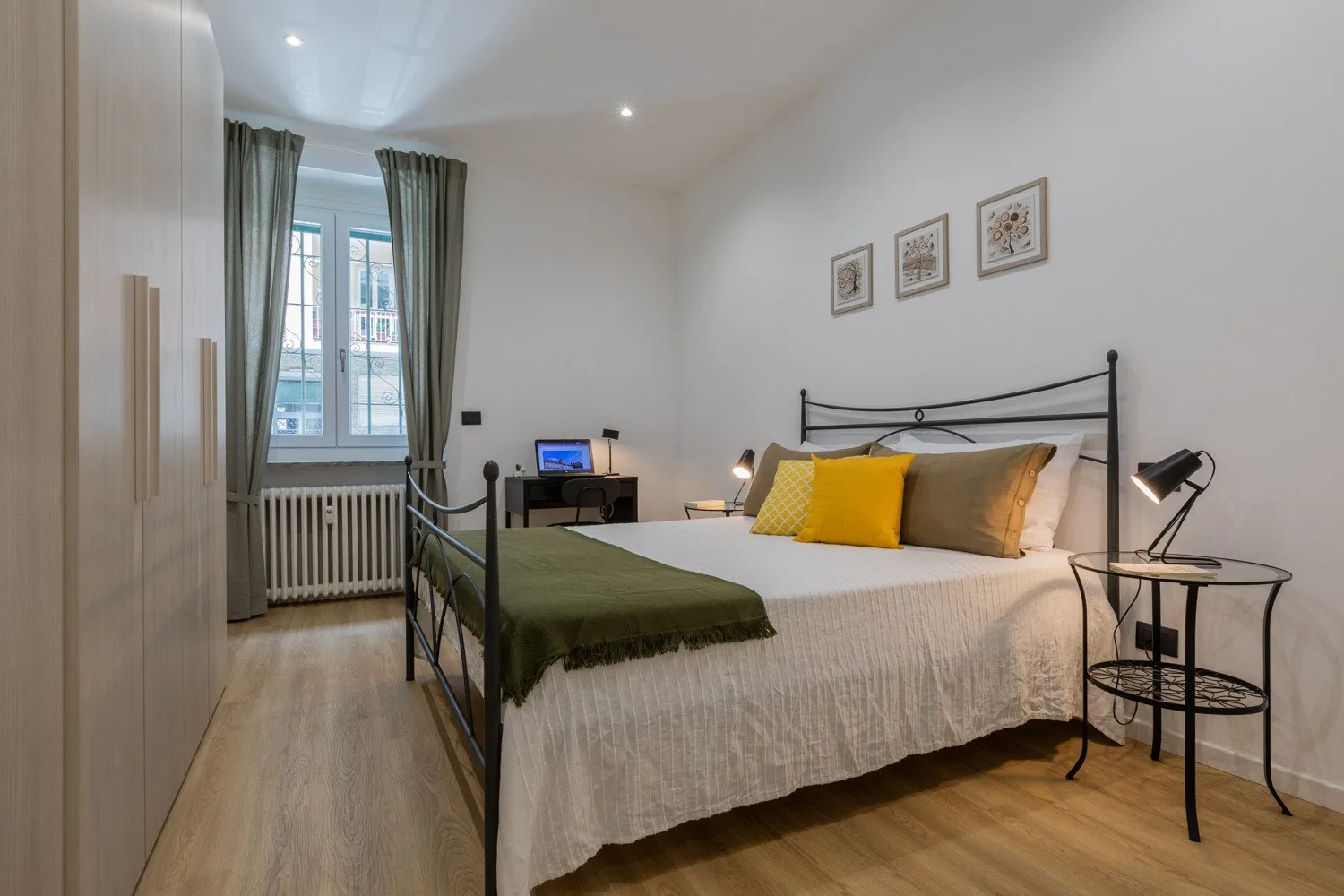 Un dormitorio con una cama, mesitas de noche y una ventana con cortinas.