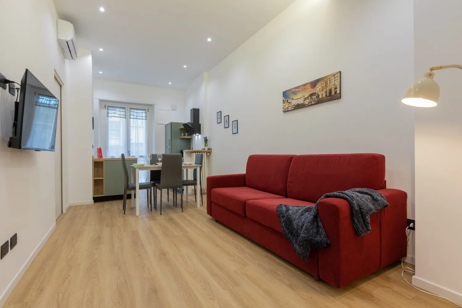 Sala de estar y comedor con asientos rojos y una mesa junto a las ventanas.