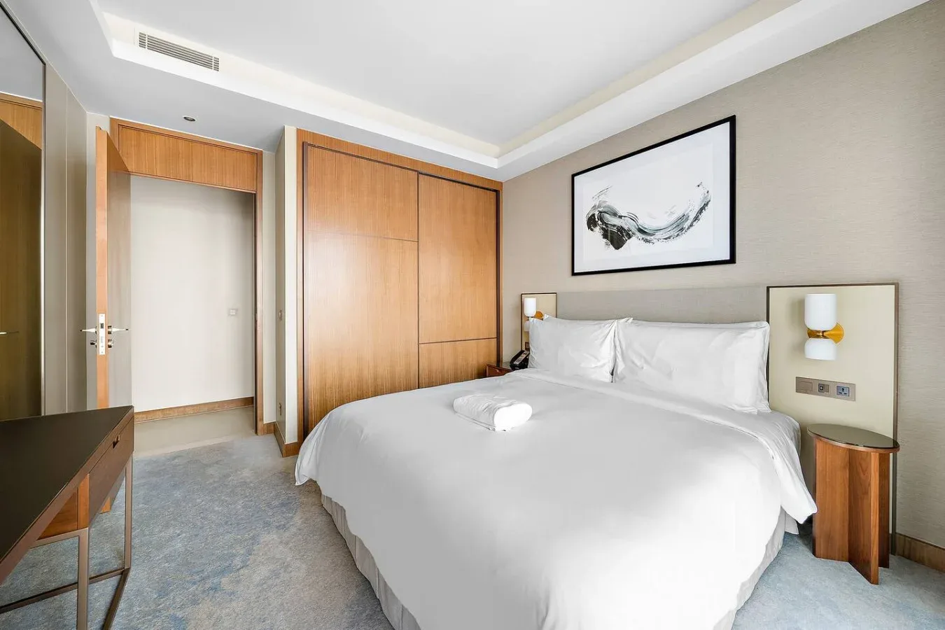 Un dormitorio con una cama grande, armarios de madera y un cuadro enmarcado.