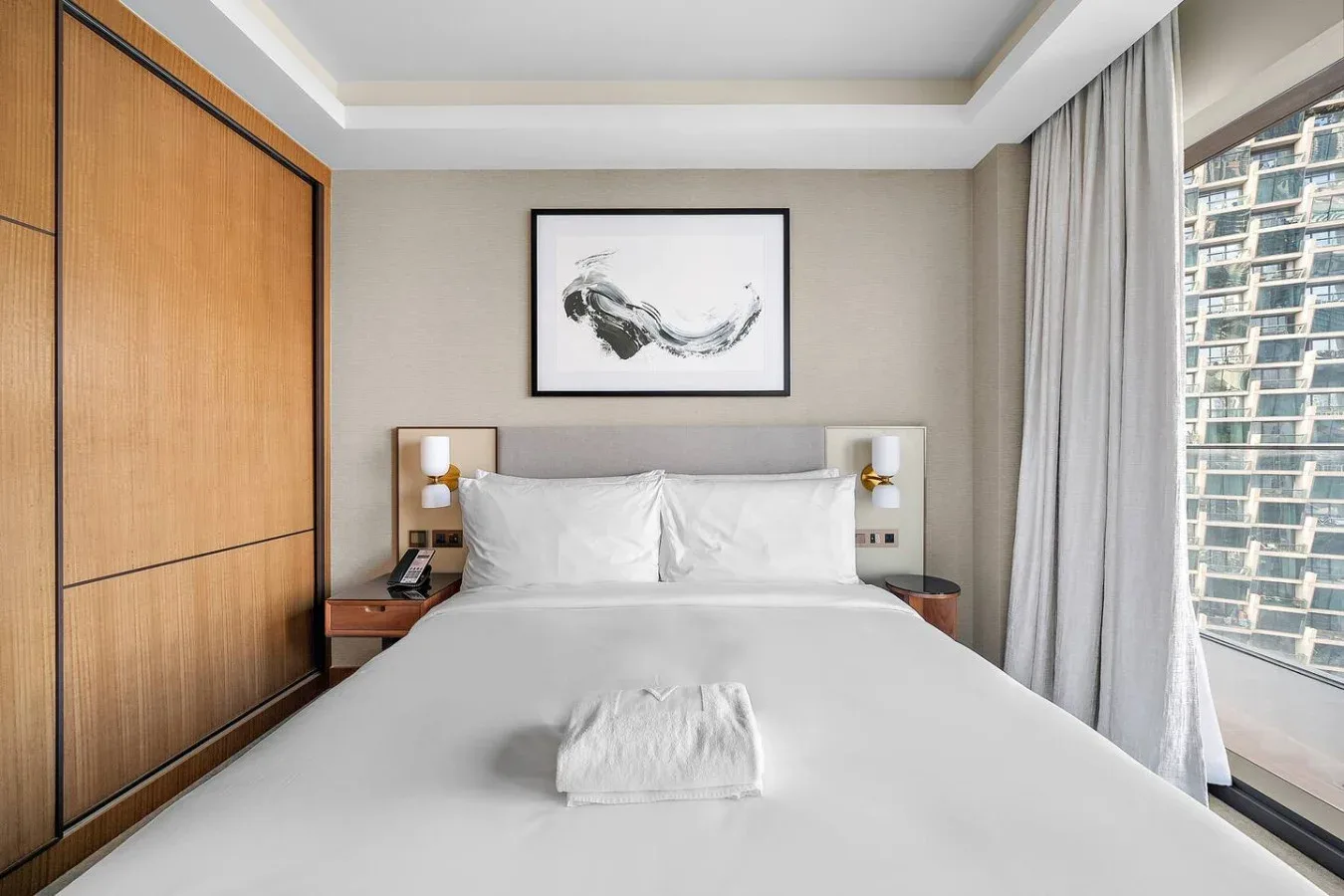 Dormitorio con una cama bien tendida bajo una obra enmarcada.