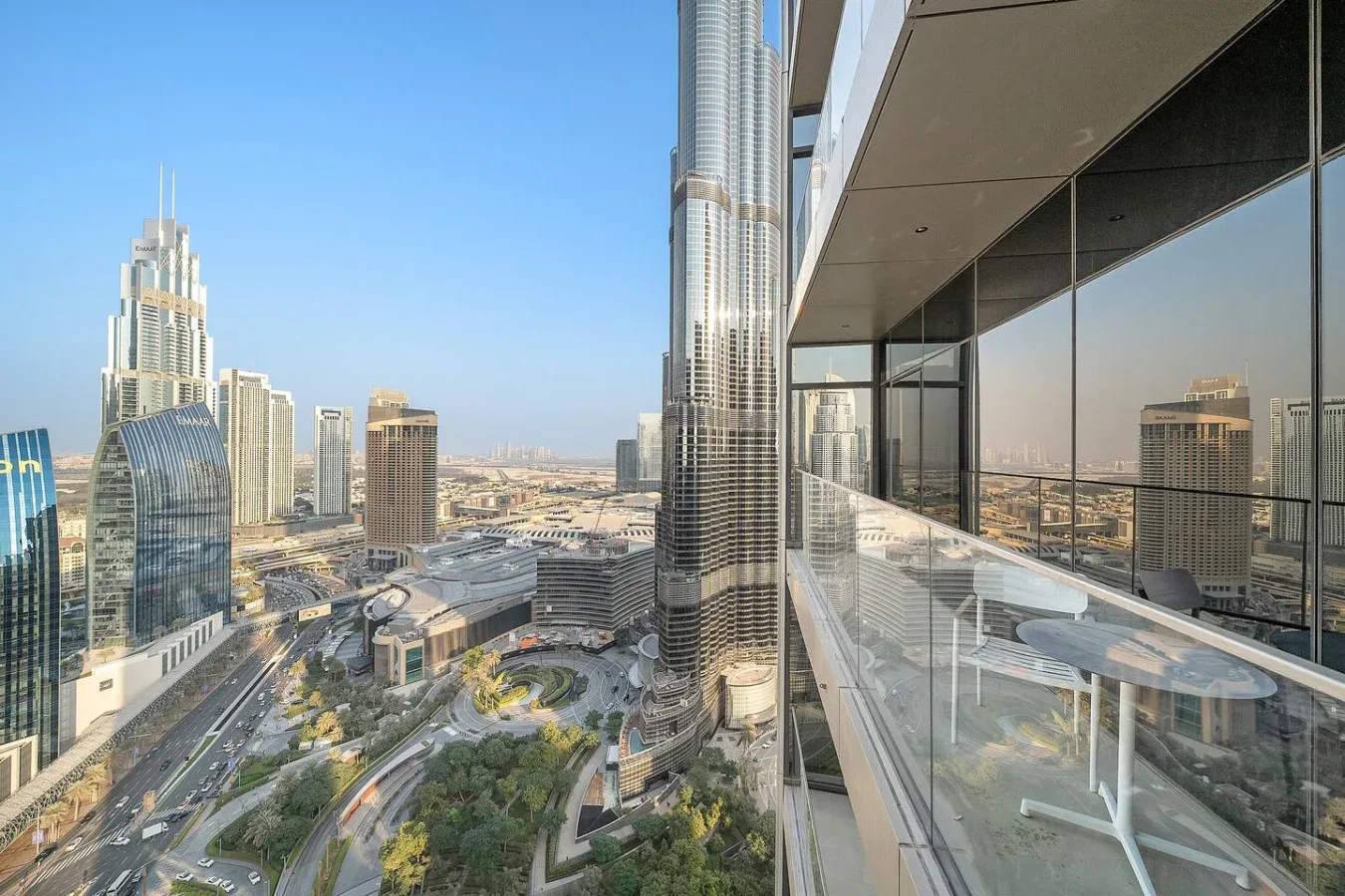 Vista del horizonte urbano desde un balcón de vidrio, con edificios altos y vías abajo.