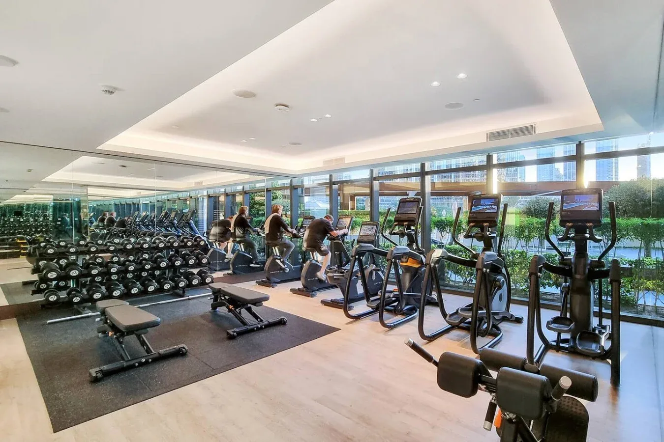 Un gimnasio luminoso con máquinas de ejercicio, pesas y grandes ventanales.