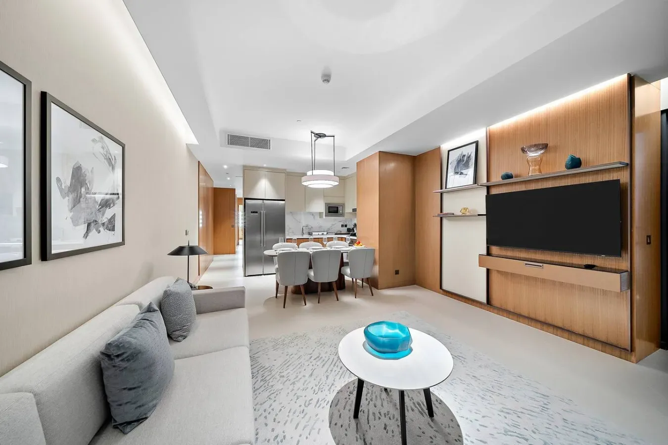 Una sala de estar y comedor moderna con asientos, una mesa y un televisor en la pared.