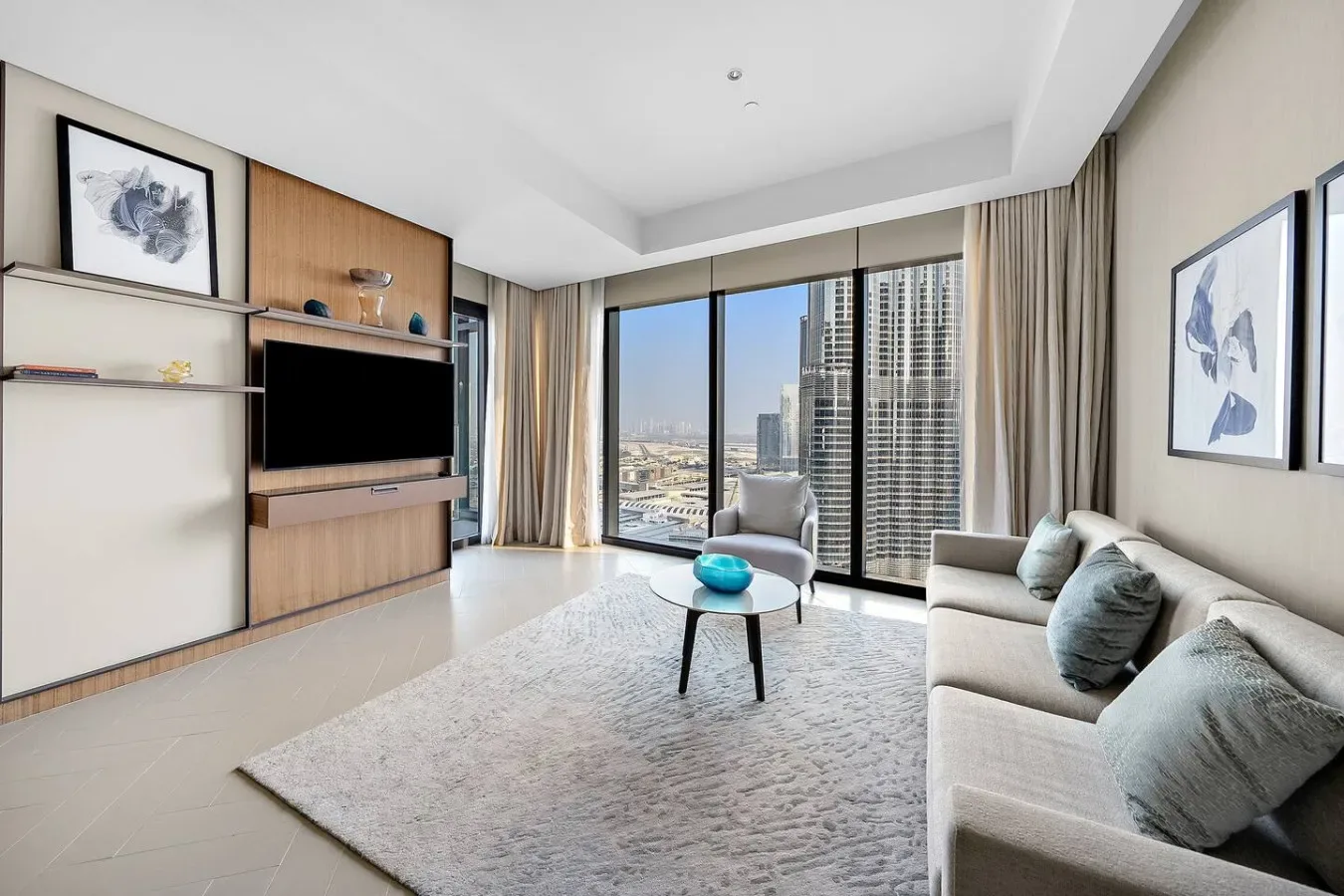 Una sala de estar luminosa con zona de asientos, mesa de centro y grandes ventanales con vistas a la ciudad.