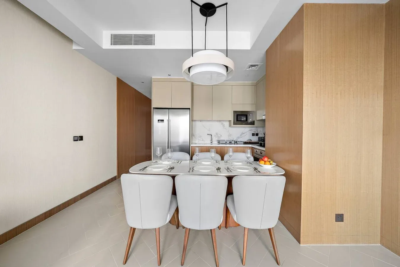 Un comedor con mesa y asientos está frente a una cocina abierta.