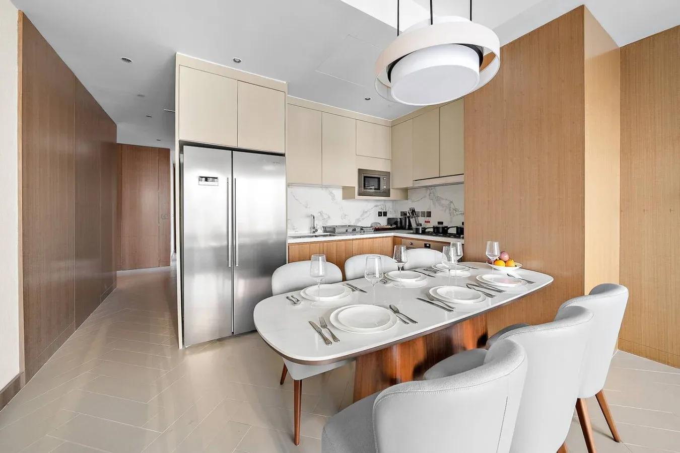 Una cocina moderna con comedor, una mesa puesta y asientos de color claro.