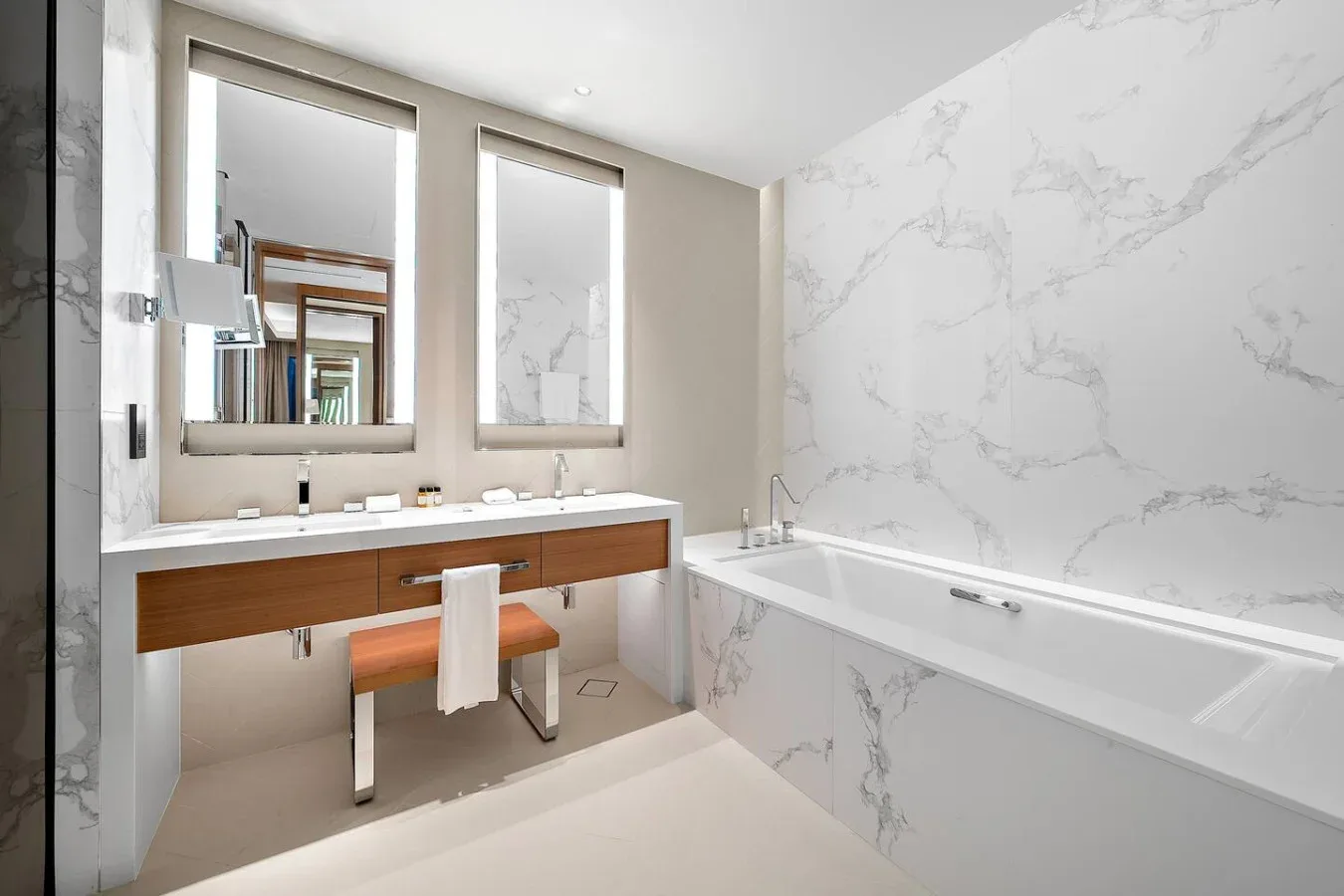 Un baño moderno con una bañera larga y un lavabo bajo dos espejos.