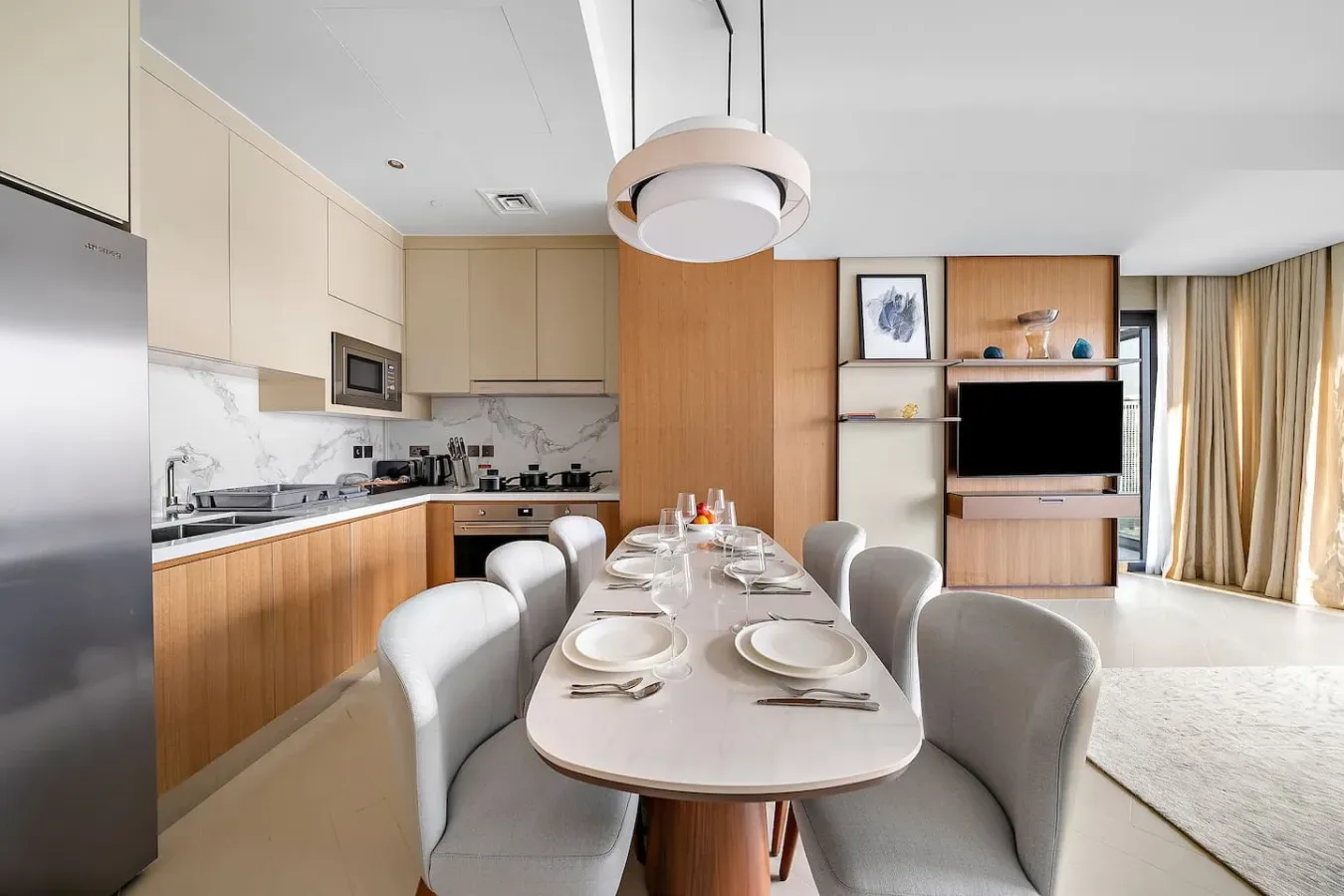 Comedor con una mesa larga y sillas junto a una cocina abierta.