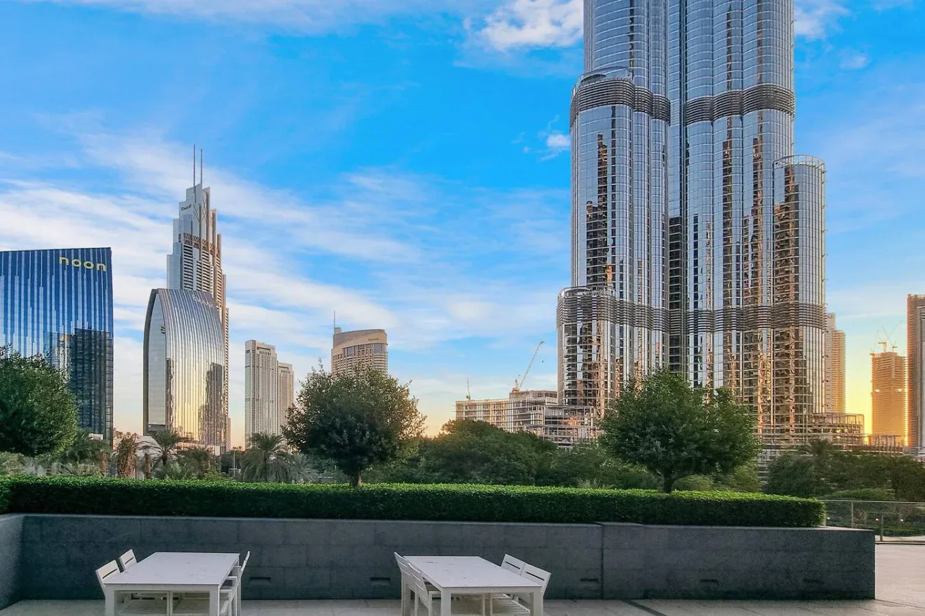 Un horizonte urbano se eleva detrás de una terraza ajardinada con asientos al aire libre.