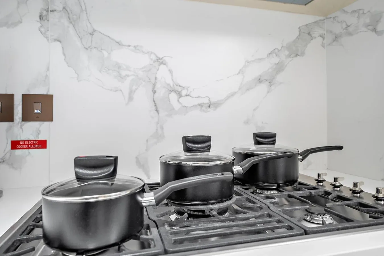 Una estufa de cocina con varias ollas bajo un salpicadero blanco veteado.