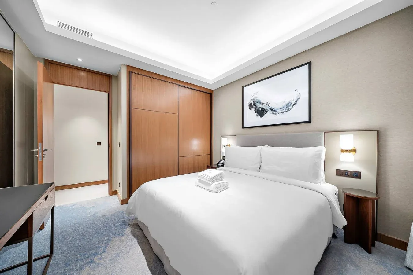 Dormitorio con una cama grande, armario panelado en madera y una obra enmarcada.
