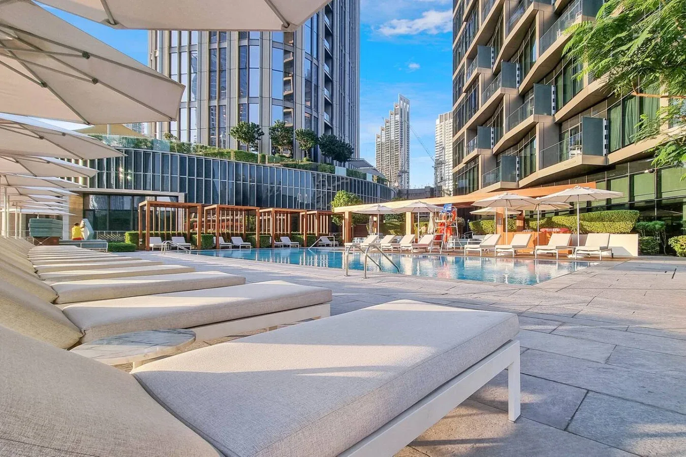 Una piscina al aire libre rodeada de tumbonas y edificios modernos.