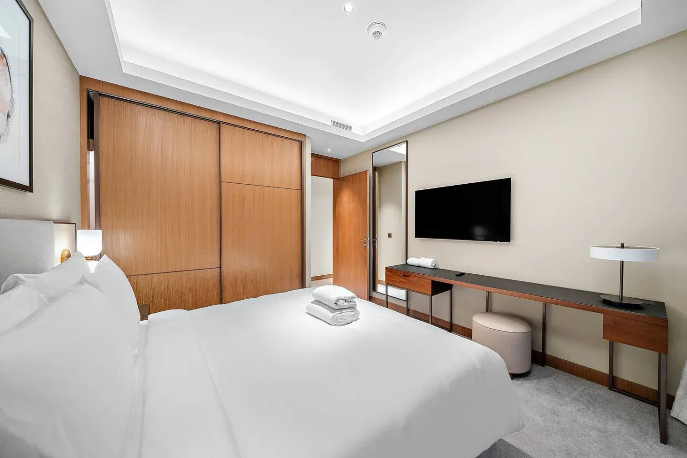 Un dormitorio con una cama bien tendida, armarios de madera y un televisor.