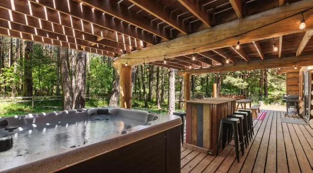 Una terraza exterior cubierta con una bañera de hidromasaje y una barra.