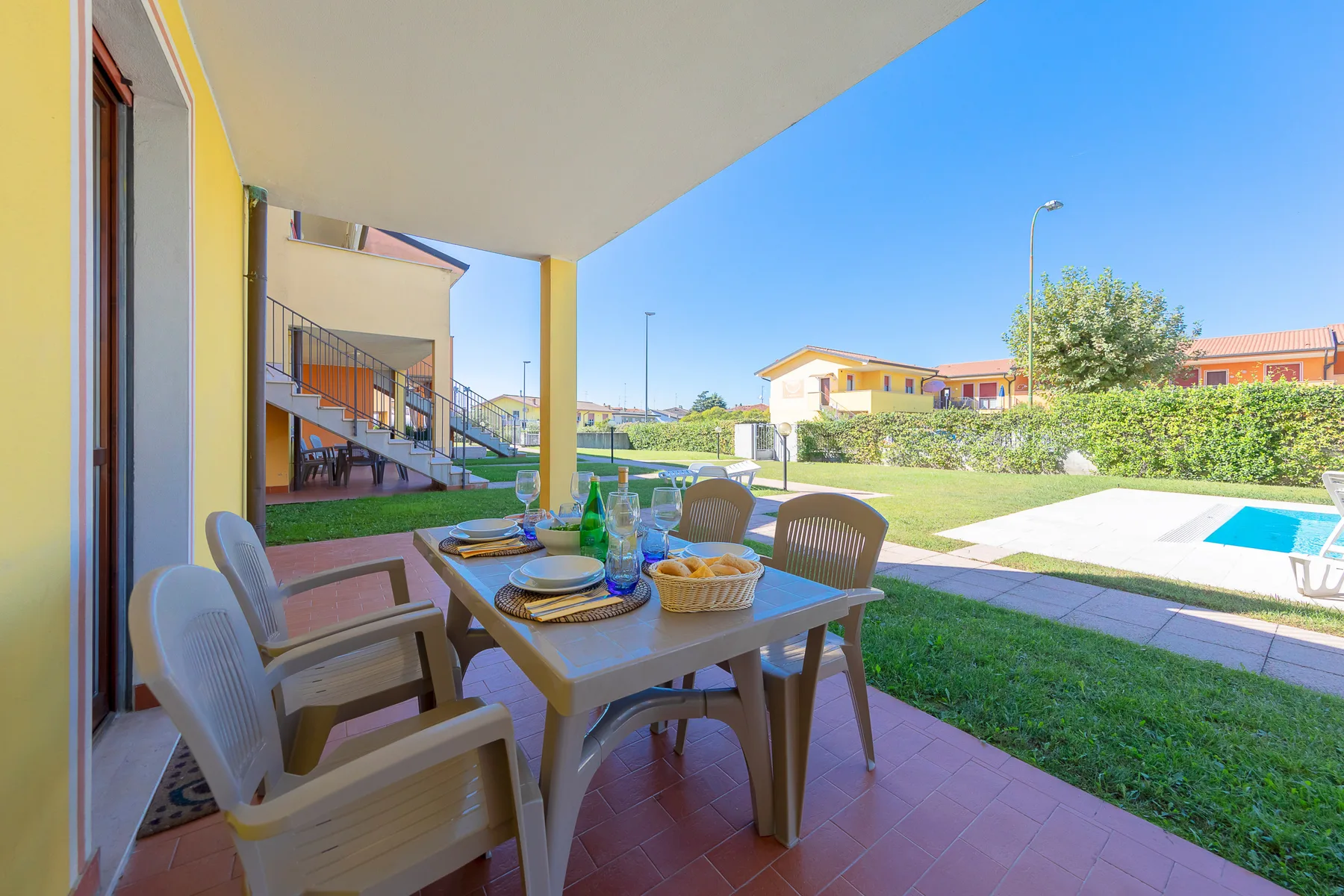 Un patio cubierto con asientos al aire libre da a un césped y una piscina.