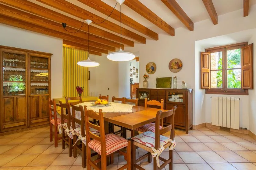 A dining room with a wooden table and chairs beneath exposed ceiling beams.