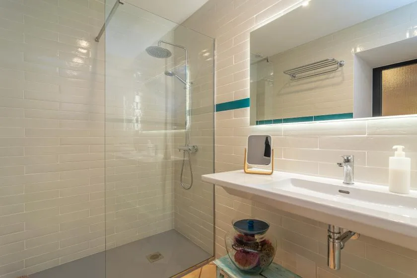 A bright bathroom with a glass shower and a long sink counter.
