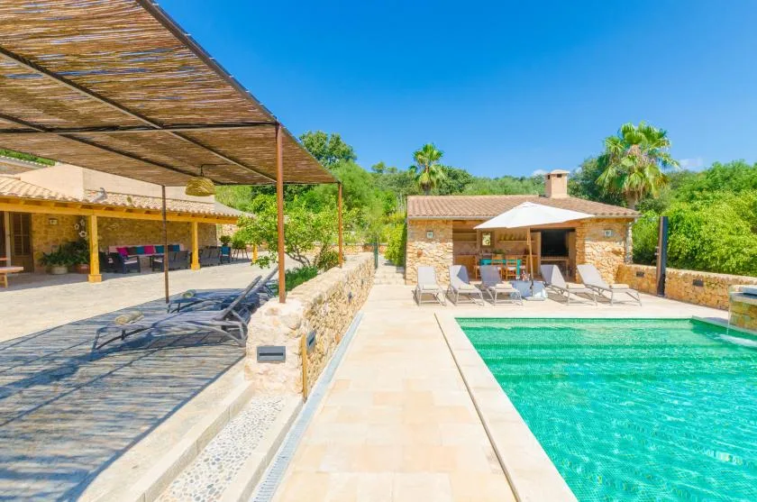 A swimming pool beside a stone pavilion and a shaded outdoor seating area.