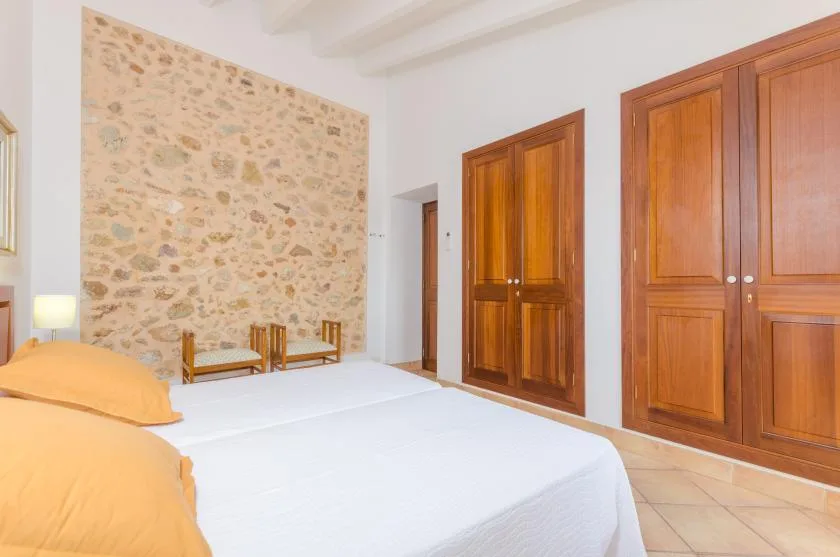 A bedroom with beds, wooden doors, and a stone accent wall.