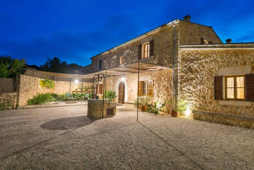 A stone building surrounds a spacious paved courtyard with a canopy and outdoor seating.