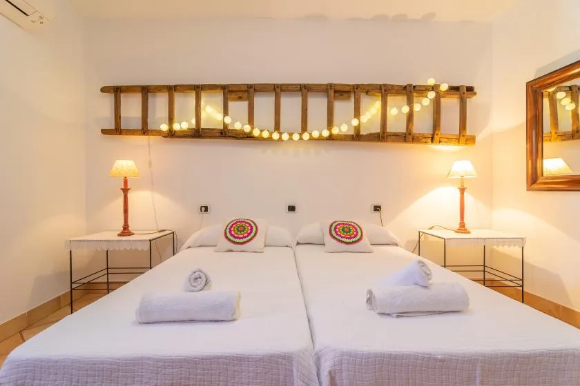 A bedroom with two beds, colorful pillows, and bedside lamps.