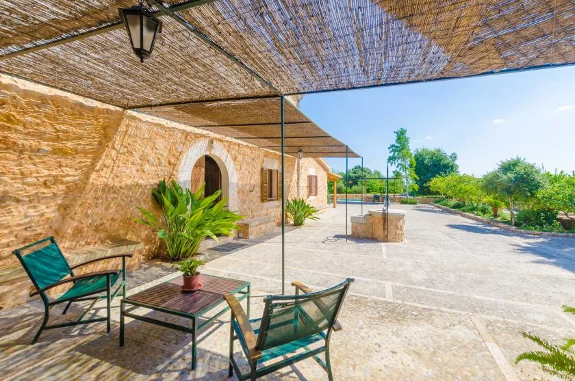 A shaded stone terrace with outdoor seating and a broad paved courtyard.