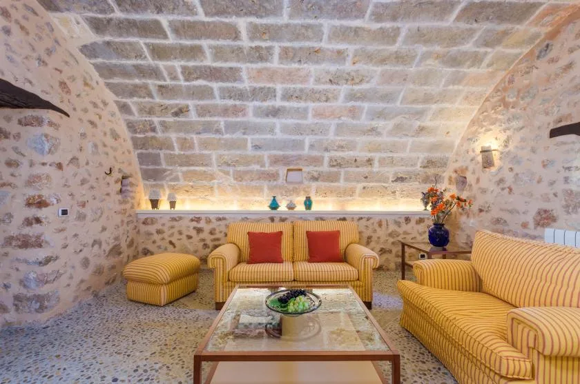 A stone-vaulted living room with striped seating and a low coffee table.