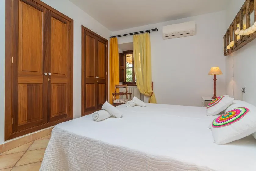 A bedroom with a large bed, wooden wardrobes, and a curtained window.