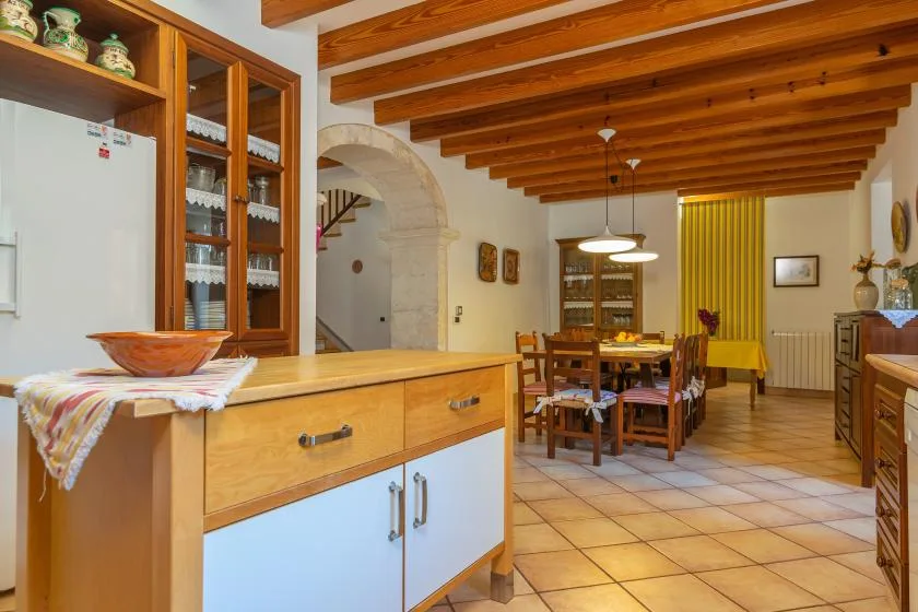A kitchen and dining area with wooden ceiling beams and a long dining table.